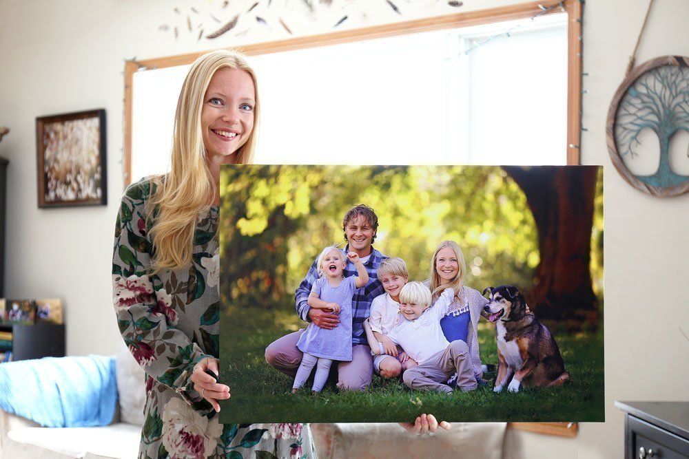 Mujer con un gran lienzo fotográfico con una foto de familia en la mano