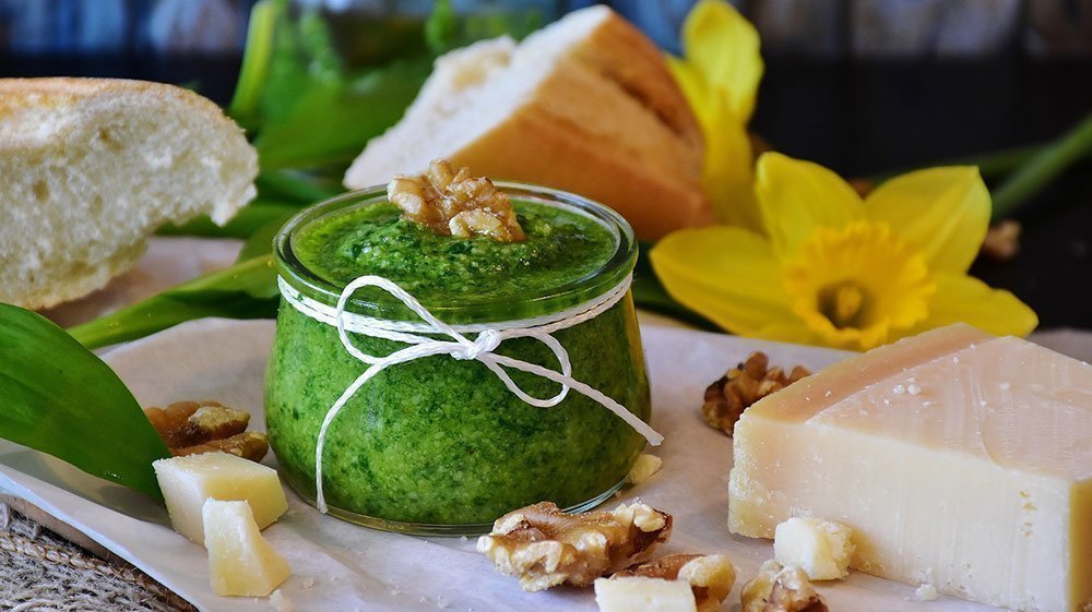 Pesto verde casero decorado en una copa con pan, queso y nueces