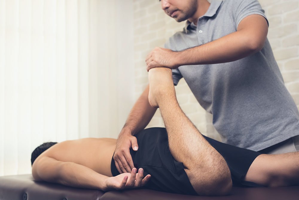 Un joven es tratado con un masaje deportivo por un fisioterapeuta